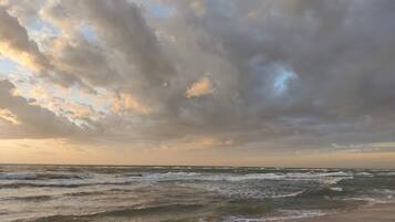 A beach with waves and a cloudy sky.