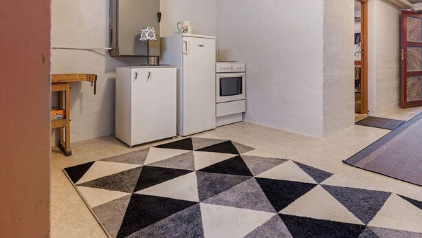 A compact kitchen with a refrigerator, oven, and a small table with a lamp. - 11 Person Holiday Home in Tarva (Orland)