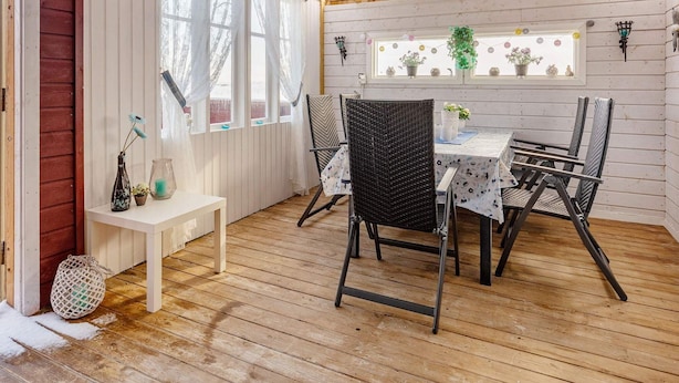 A wooden deck with a table and chairs, a bench, and a window with curtains. - 11 Person Holiday Home in Tarva (Orland)