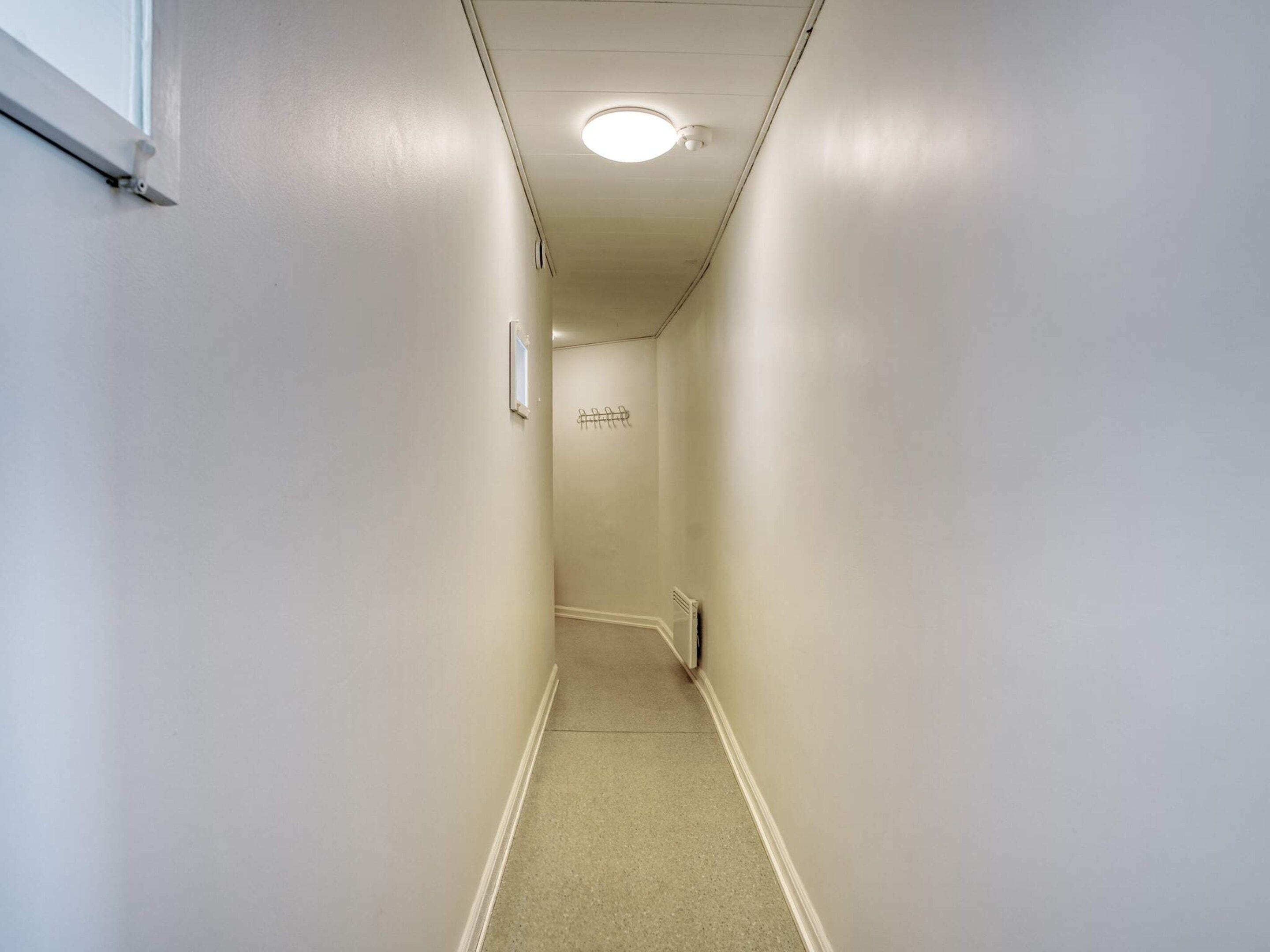 A narrow, well-lit hallway with a radiator and a light fixture on the ceiling.