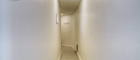 A narrow, well-lit hallway with a radiator and a light fixture on the ceiling.