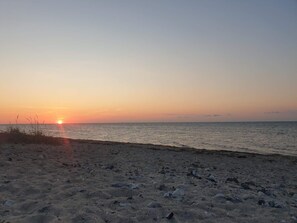 Une plage avec un coucher de soleil sur l’océan.