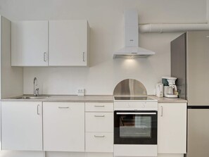 A modern kitchen with white cabinetry, a stainless steel range hood, a built-in oven, and a coffee maker. - 4 Person Holiday Home in Nakskov (Nakskov)