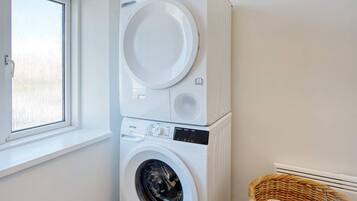 A stacked washer and dryer unit in a room with a window.
