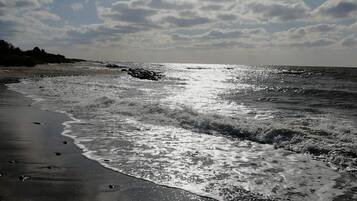 A beach with waves, a clear sky, and a distant shoreline.
