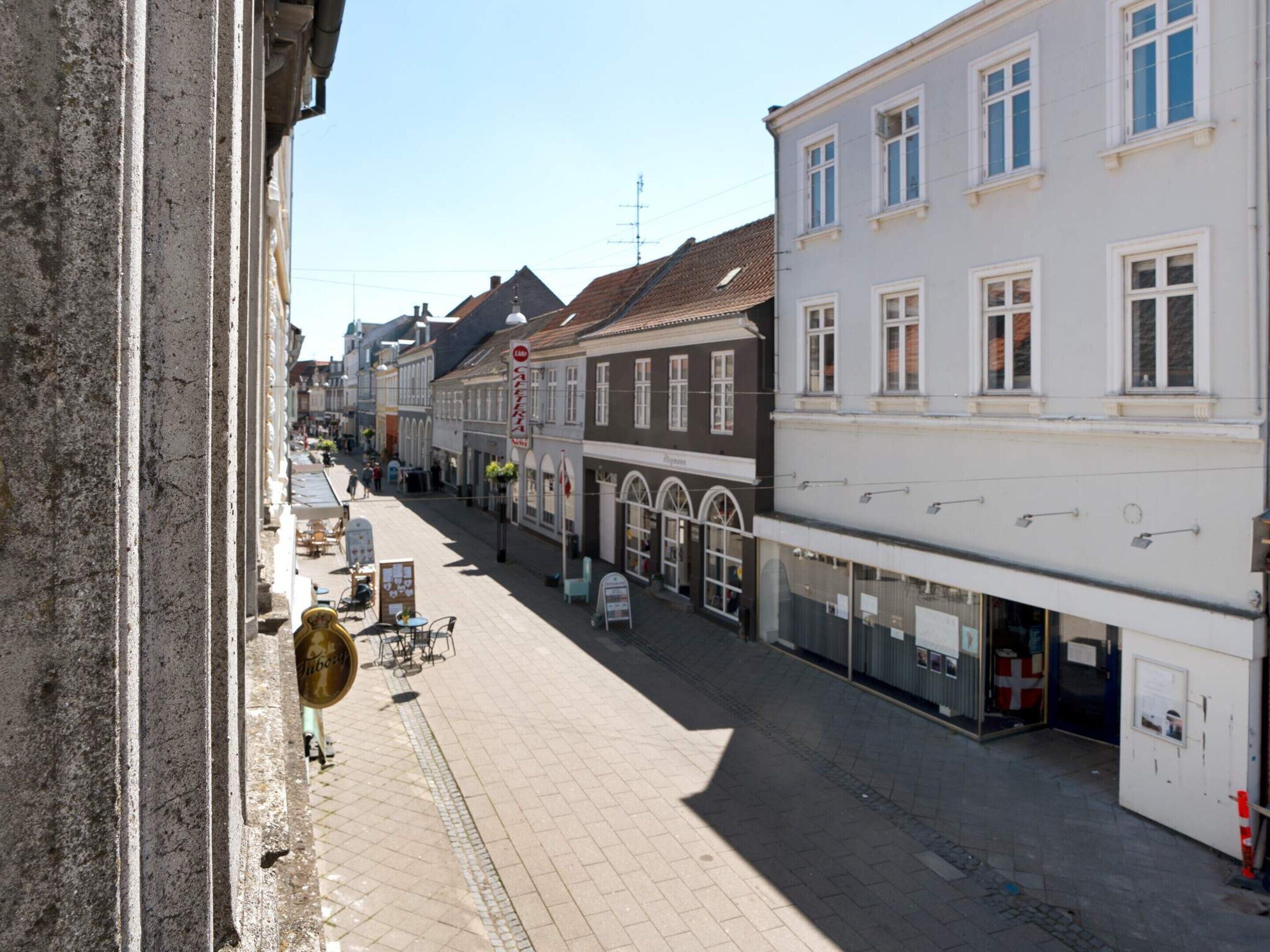 A street with buildings, a signboard, and a clear sky.