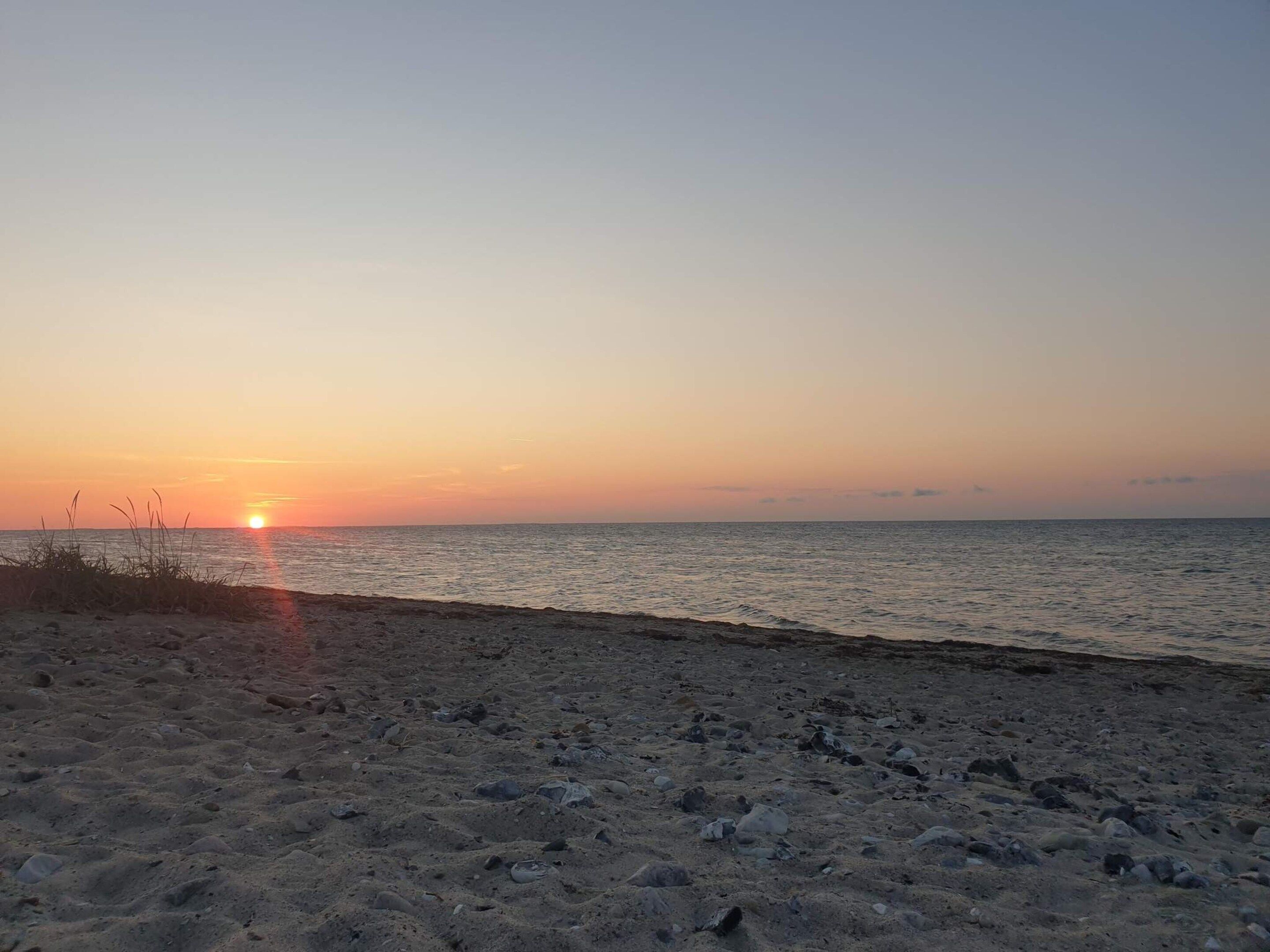 A beach with a sunset over the ocean.