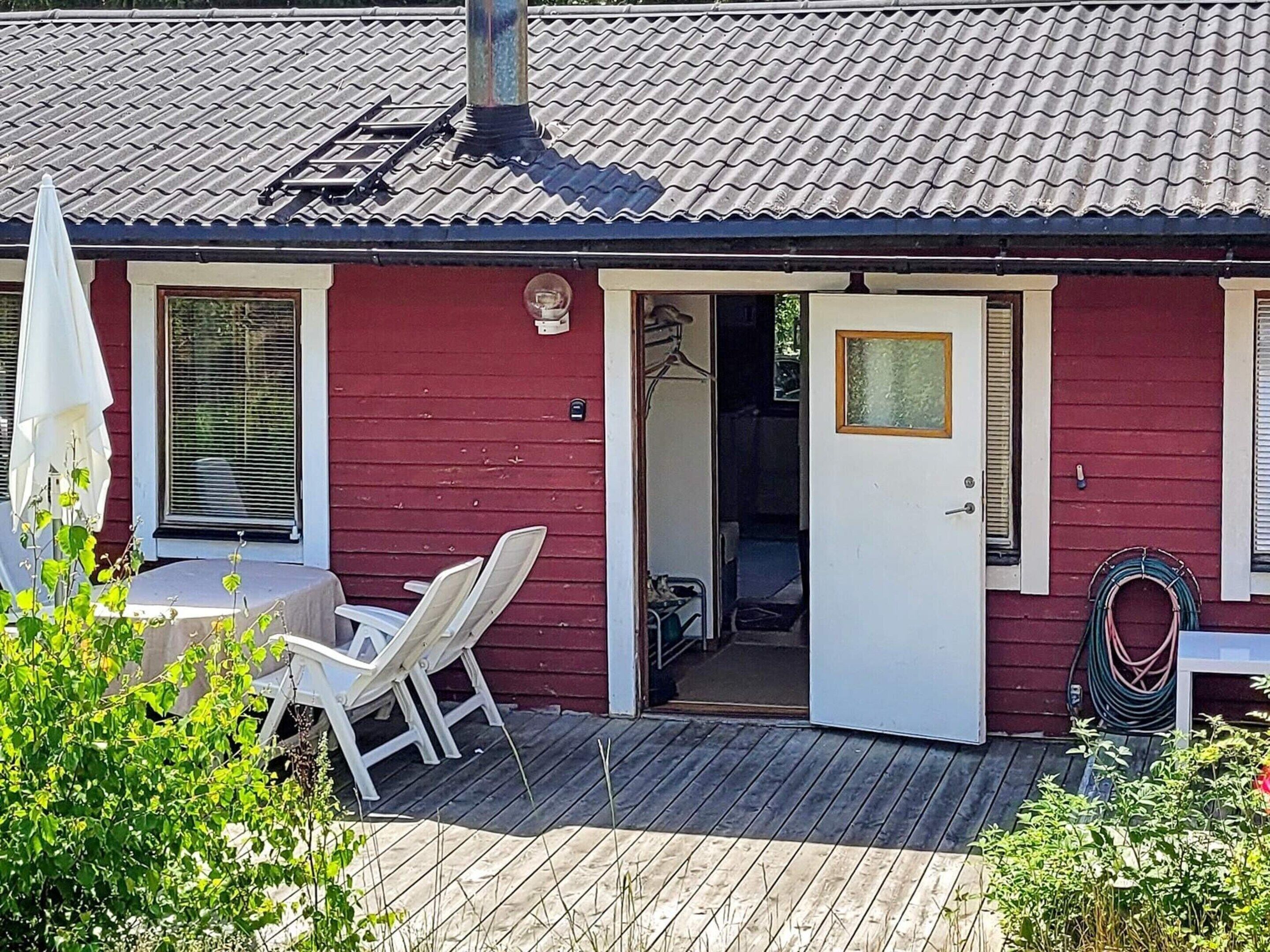 A red building with a tiled roof, a door, and a small outdoor seating area with a table and chairs.