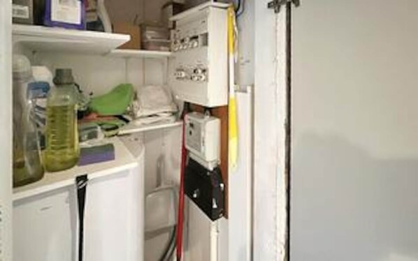 A kitchen with a refrigerator, microwave, and various kitchen items on the counter.
