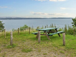 Une table de pique-nique entourée d’une barrière faite de cordes, avec vue sur un lac.