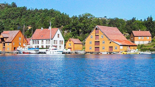 A waterfront village with traditional wooden houses, a boat docked in the water, and a clear blue sky. - 6 Person Holiday Home in Svelgen-by Traum (Bremanger)