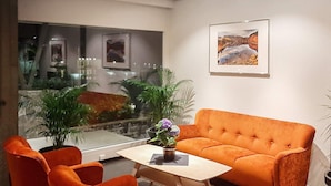 A modern living room with a sofa and two armchairs, a coffee table, and a large window with a view of a cityscape. - 6 Person Holiday Home in Svelgen-by Traum (Bremanger)