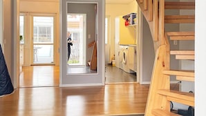 A modern home interior with a wooden floor, a laundry area with washing machines, and a staircase. - 6 Person Holiday Home in Bjorklinge-by Traum (Björklinge)