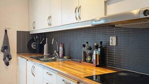 A modern kitchen with white cabinets, a black backsplash, and a wooden countertop. - 6 Person Holiday Home in Bjorklinge-by Traum (Björklinge)