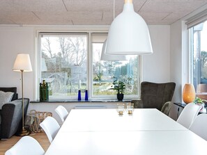 Ett modernt matområde med ett vitt bord, stolar och en hängande taklampa.