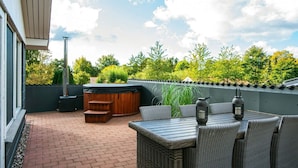 Une terrasse extérieure dotée d’un jacuzzi, d’un espace salon et d’une cheminée.