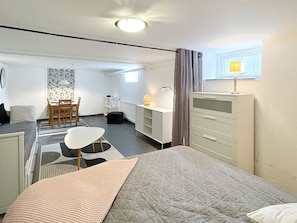 A compact hotel room with a bed, a desk, a chair, a small table, and a wardrobe. - 4 Person Holiday Home in Ystad-by Traum (Ystad)