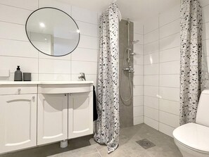 A bathroom with a white sink, mirror, shower, and toilet. - 4 Person Holiday Home in Ystad-by Traum (Ystad)