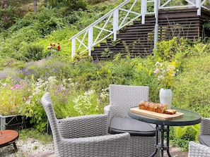 An outdoor seating area with wicker furniture, a table with a loaf of bread, and a vase of flowers. - 4 Star Holiday Home in Ingaro (Ingaro)