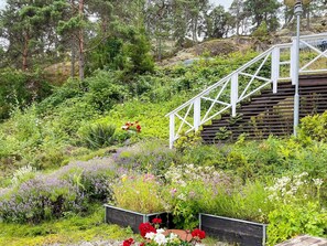 A garden with a wooden staircase leading up a slope, surrounded by various plants and flowers.