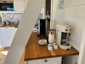 Eine Küche mit einer Holzausziehtischplatte, einer Kaffeemaschine und einer Mikrowelle.