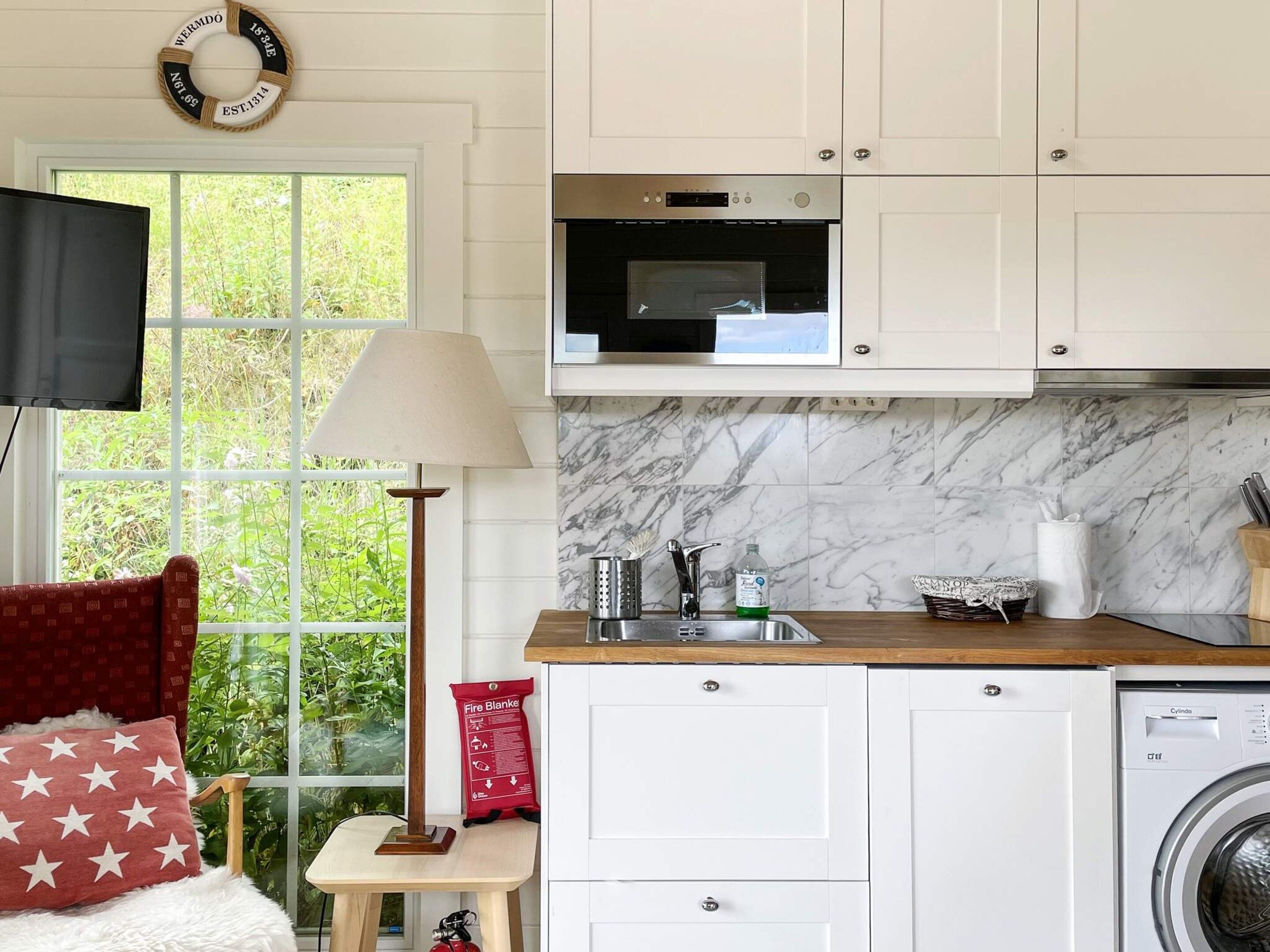 A compact kitchen with a microwave, sink, and washing machine.