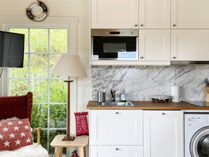 A compact kitchen with a microwave, sink, and washing machine.