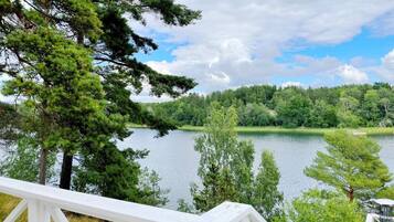 A lakeside view with a white deck overlooking the water, surrounded by trees and a clear sky.
