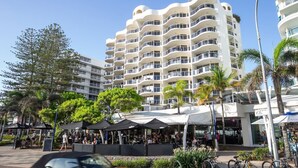 A multi-story hotel with balconies, outdoor seating, and palm trees. - ZANZIBAR APT 802- OCEAN VIEW APARTMENT (Mooloolaba)