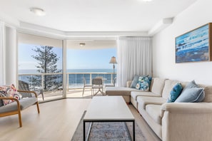 Relax in this stylish living room with a sofa, coffee table, and balcony offering ocean views.