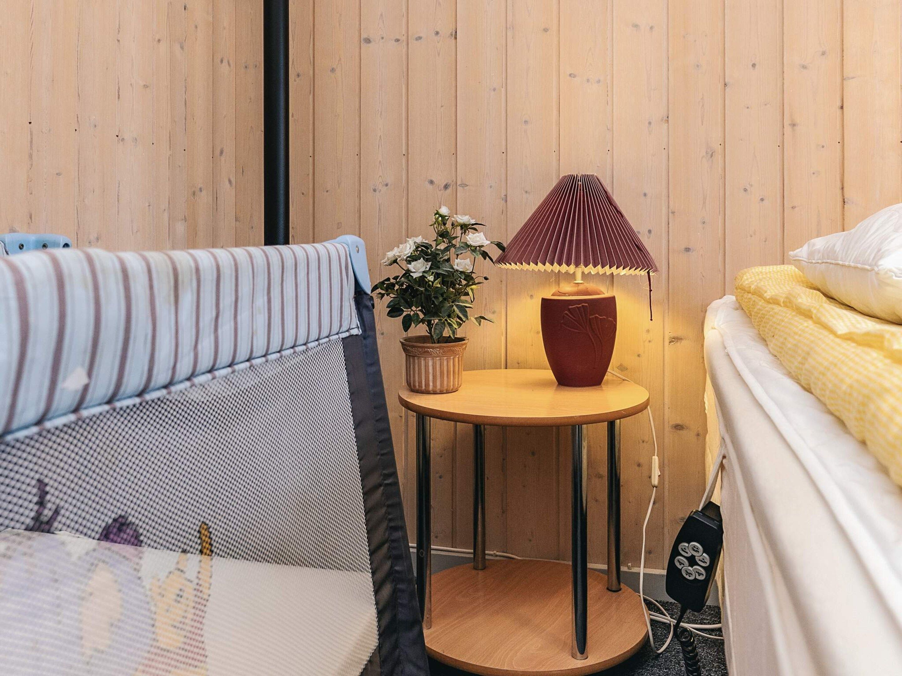 Ein Zimmer mit zwei Betten, einem kleinen runden Tisch mit Lampe und einer Topfpflanze.