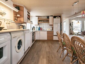 A modern kitchen with built-in appliances, wooden cabinets, and a dining area with wicker chairs.