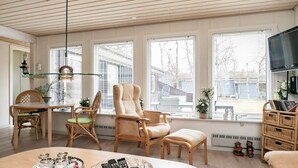 A living room with a round table, two chairs, a sofa, and a television. - 8 Person Holiday Home in Hals (Hals)
