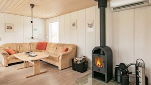 A cozy living room with a beige sofa, a round wooden coffee table, and a black wood-burning stove. - 8 Person Holiday Home in Hals (Hals)