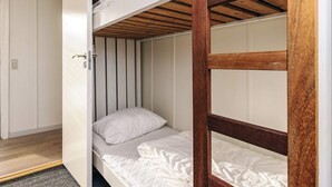 A bunk bed with a wooden frame and white bedding, a door with a handle, and a ceiling with wooden beams. - 8 Person Holiday Home in Hals (Hals)