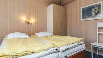 Ein Zimmer mit Holzwänden, einem Bett, einem Nachttisch, einem Sessel und einem Bild an der Wand.