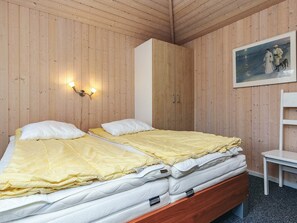 A wooden-paneled room with a bed, a nightstand, a chair, and a painting on the wall. - 8 Person Holiday Home in Hals (Hals)