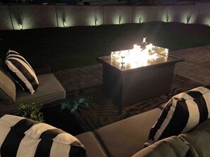 An outdoor seating area with a fire feature and cushioned chairs.