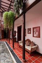 Un interior tradicional con suelo de baldosas, un banco de madera y una planta colgante.