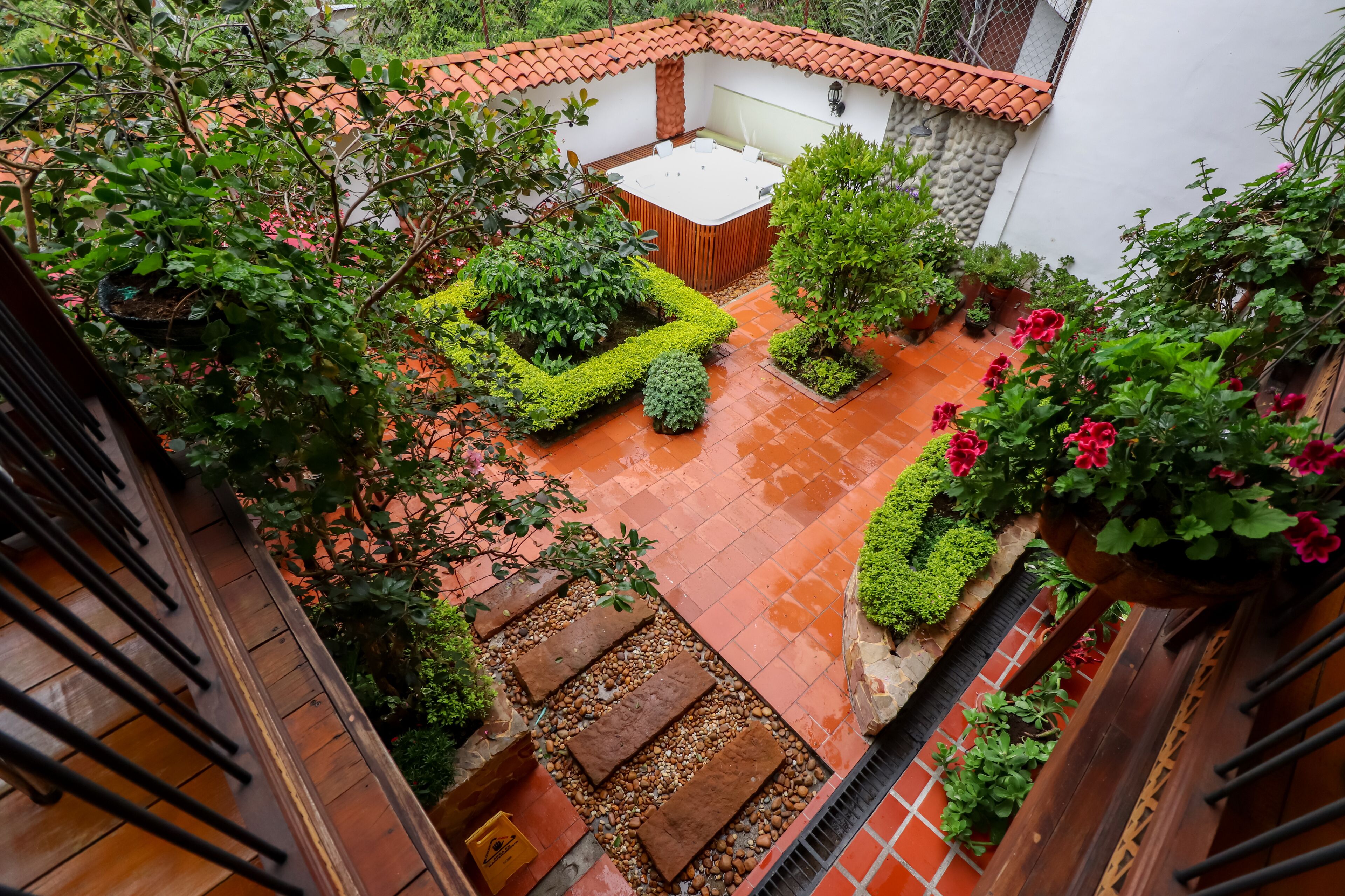 A courtyard with a hot tub, potted plants, and a tiled patio.