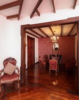 Una habitación amplia con suelo de madera, un espejo grande y una araña.