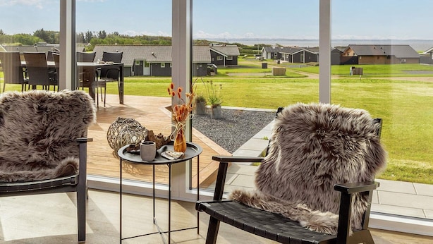 Un espace extérieur moderne, aménagé avec deux fauteuils confortables et une petite table, offrant une vue sur une pelouse bien entretenue et des immeubles résidentiels.