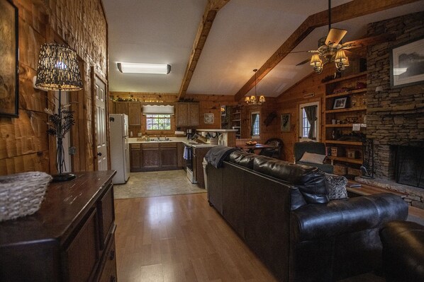 L’intérieur chaleureux d’un chalet avec un coin repas en bois, une cheminée et un canapé en cuir.