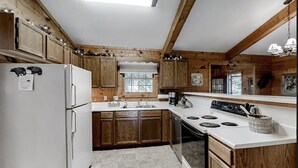 Una cocina con armarios de madera, un refrigerador blanco, una estufa y un lavamanos.