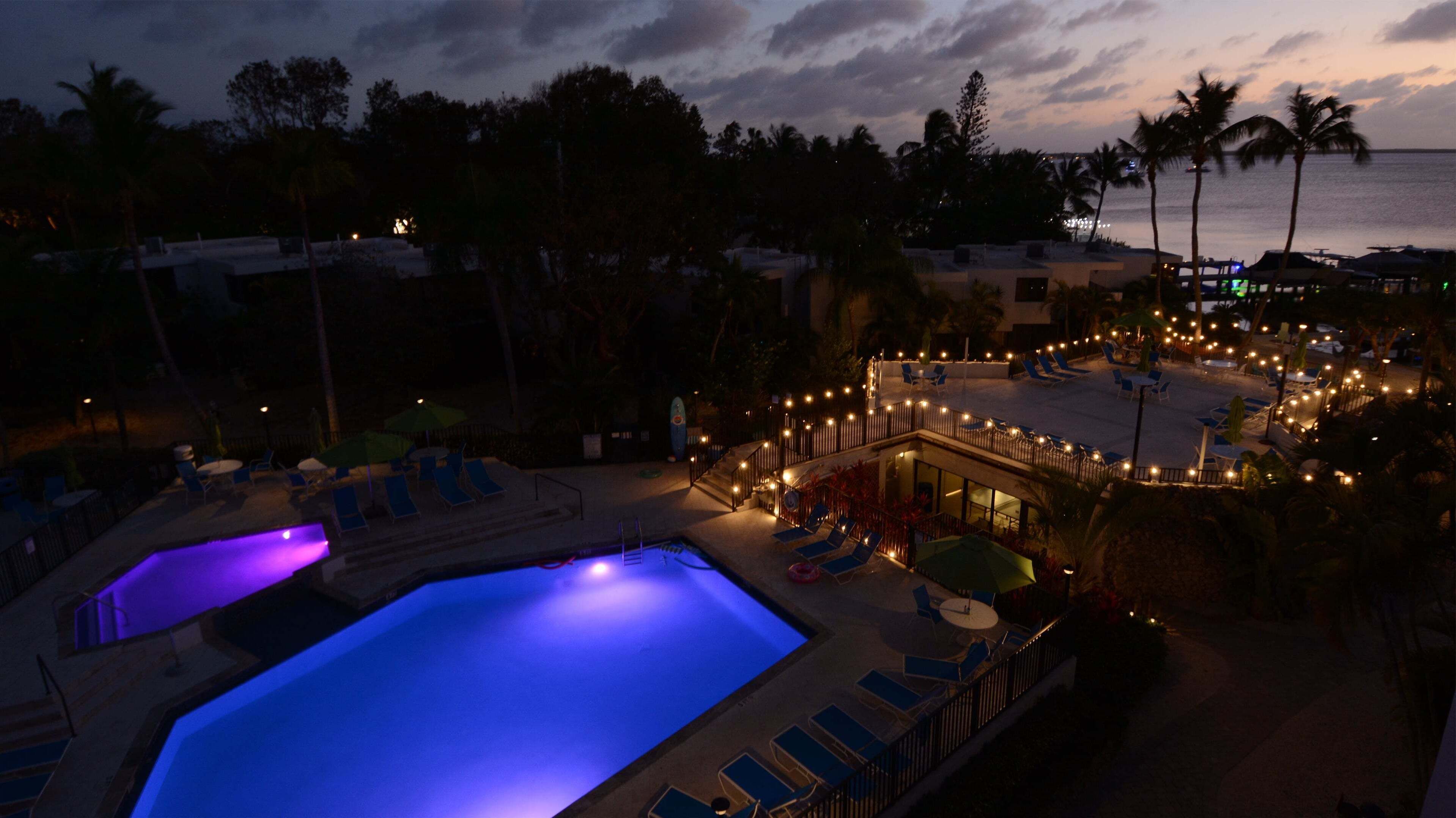 A resort with a swimming pool, lounge chairs, and a view of the ocean.