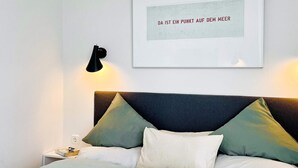 A neatly made bed with a headboard, a bedside lamp, and a framed quote on the wall.