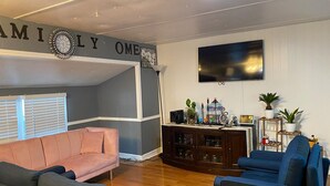 A living room with a grey accent wall, a pink sofa, a blue sofa, and a wooden entertainment center.