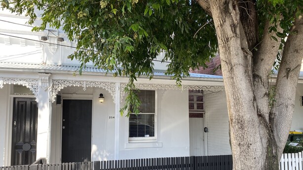A white building with a black door, a window, and a mailbox.