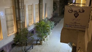 Ein Innenbereich mit einem Korridor, einem Schild für The Central House Hostel, einer Treppe, Zimmerpflanzen und einem gefliesten Boden.