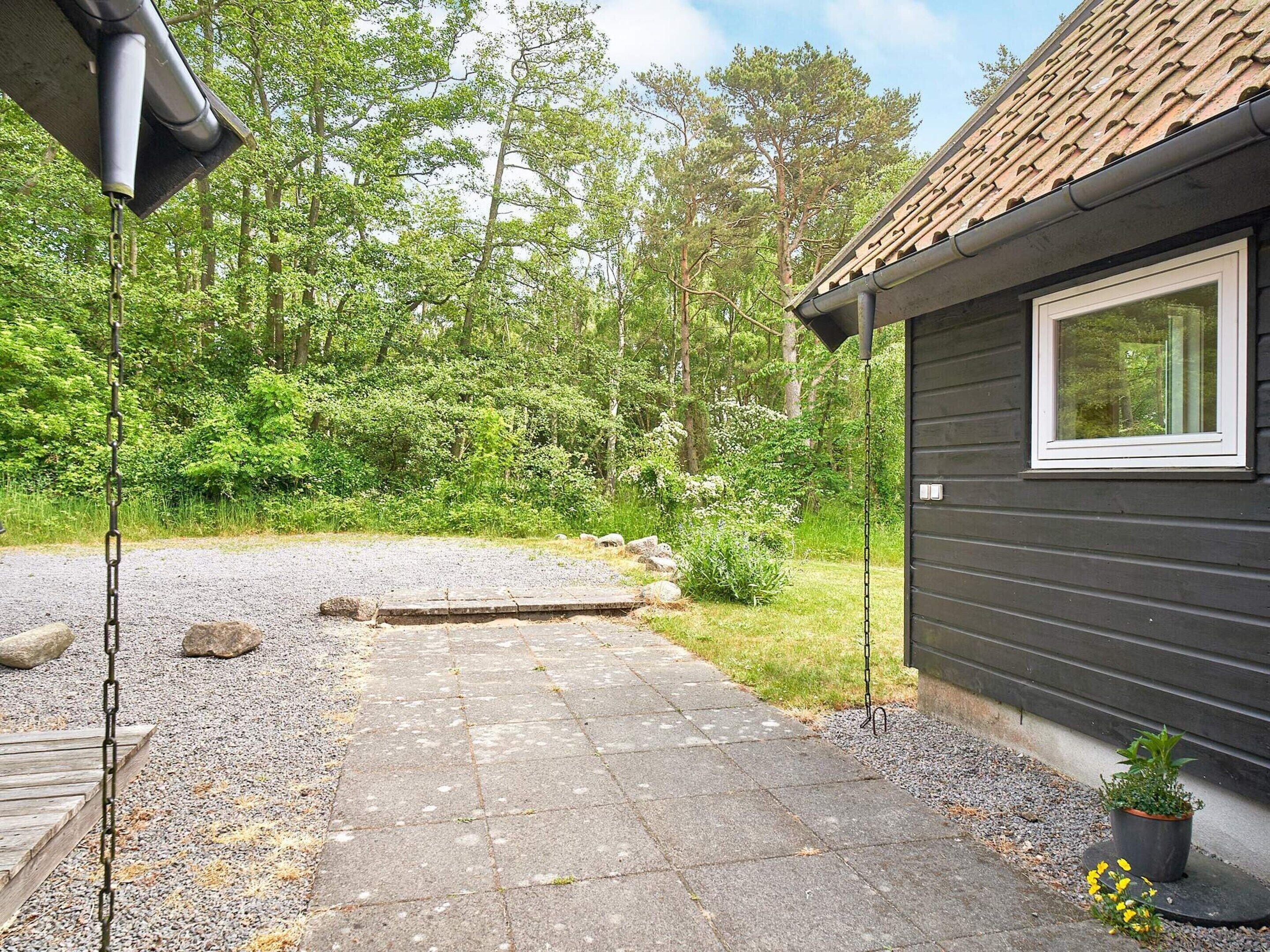 Une maison avec une allée en gravier menant à une terrasse en bois.